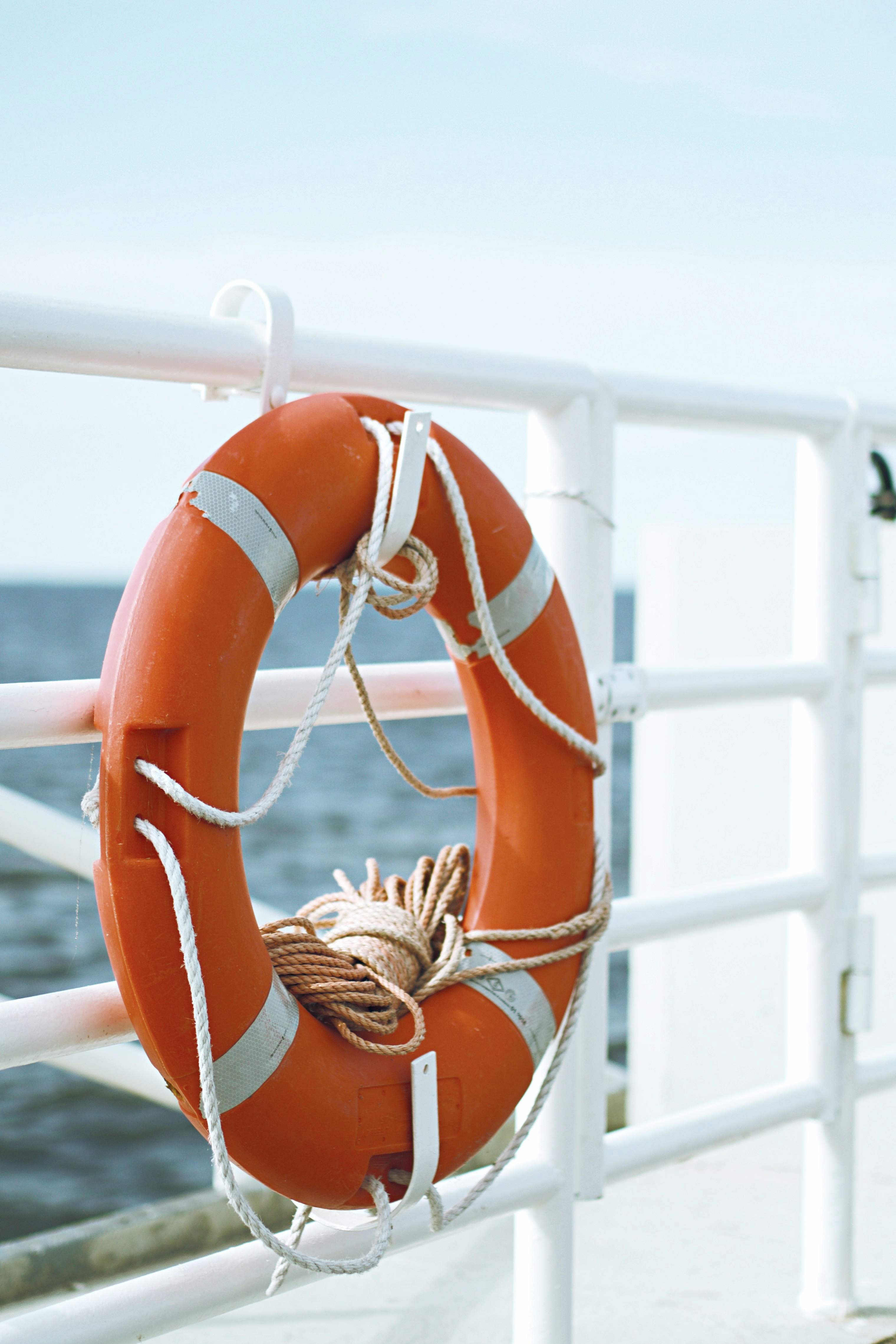 Rettungsring an einem weissen Geländer, im Hintergrund das Meer